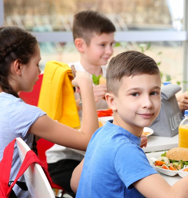 Child sitting at lunch table with lunch in a group