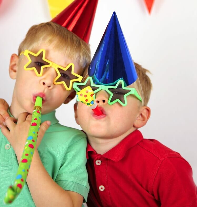 two celebrating children in part hats and glasses