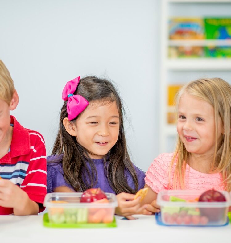 Three children eating from their lunchboxes