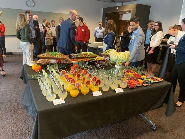 A presentation room filled with people and tables of refreshments