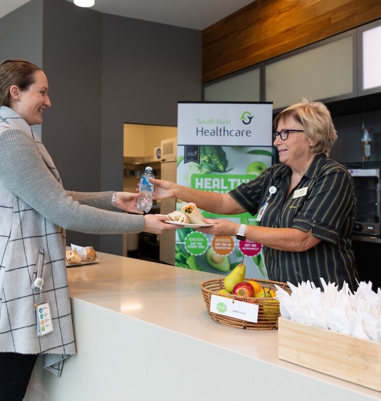 Woman serving another woman a sandwich and a bottle of water
