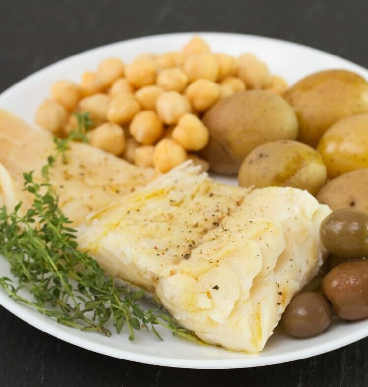 Lemon and thyme barramundi fillet served with potatoes, chickpeas, olives and sprigs of thyme