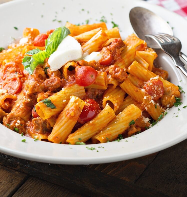 Beef ragout with rigatoni pasta in a bowl with a spoon resting on it