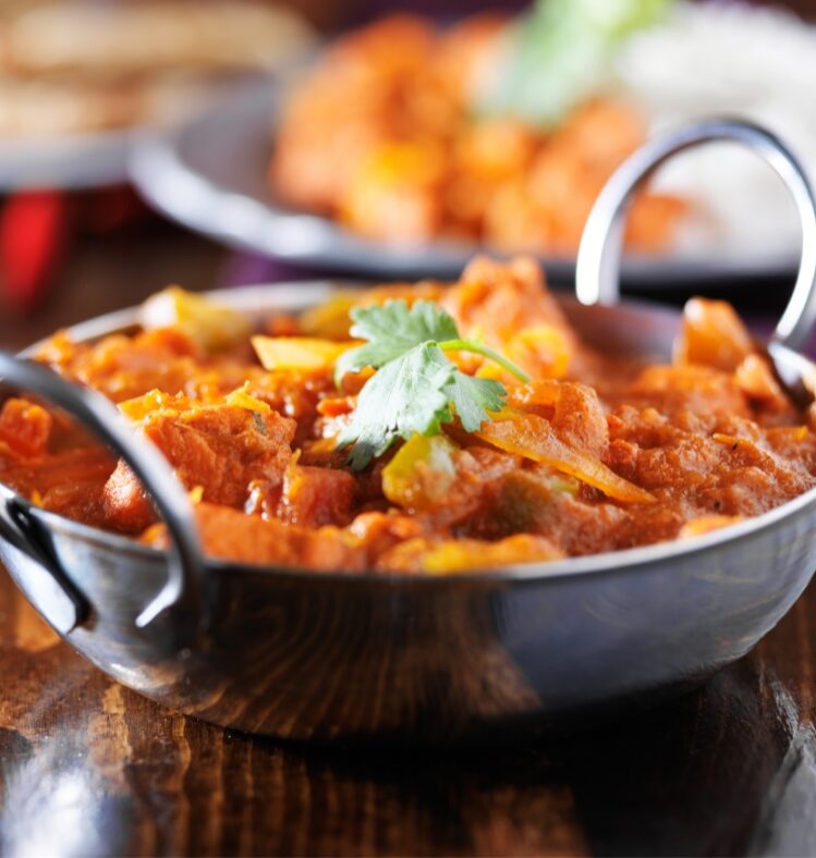Chicken curry in a metal dish with two round handles