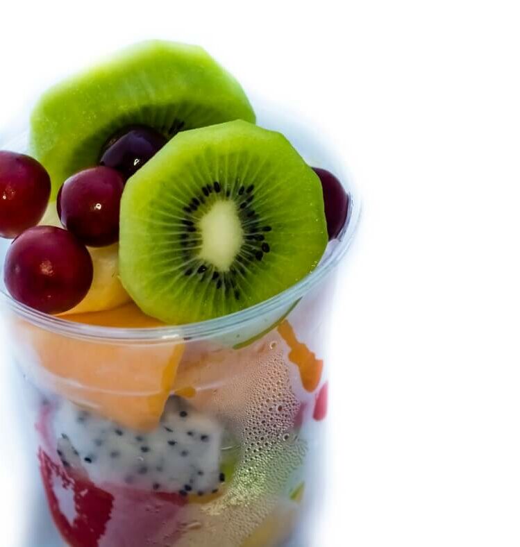 a cup of fruits including kiwis, grapes and dragonfruits