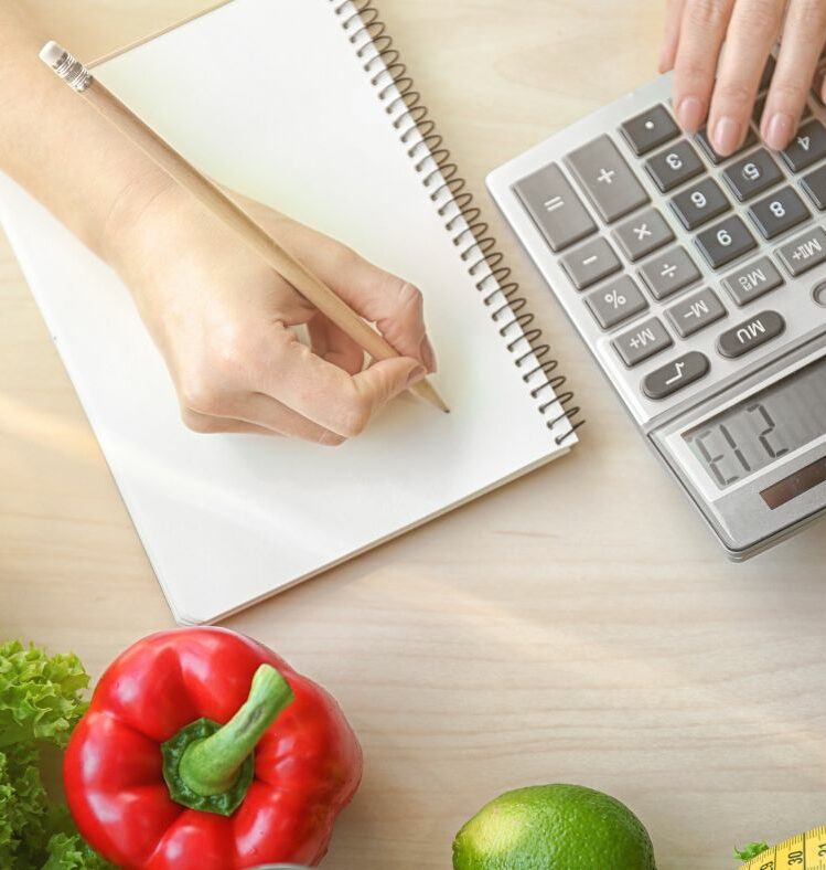 Person writing on a notepad and typing on a calculator